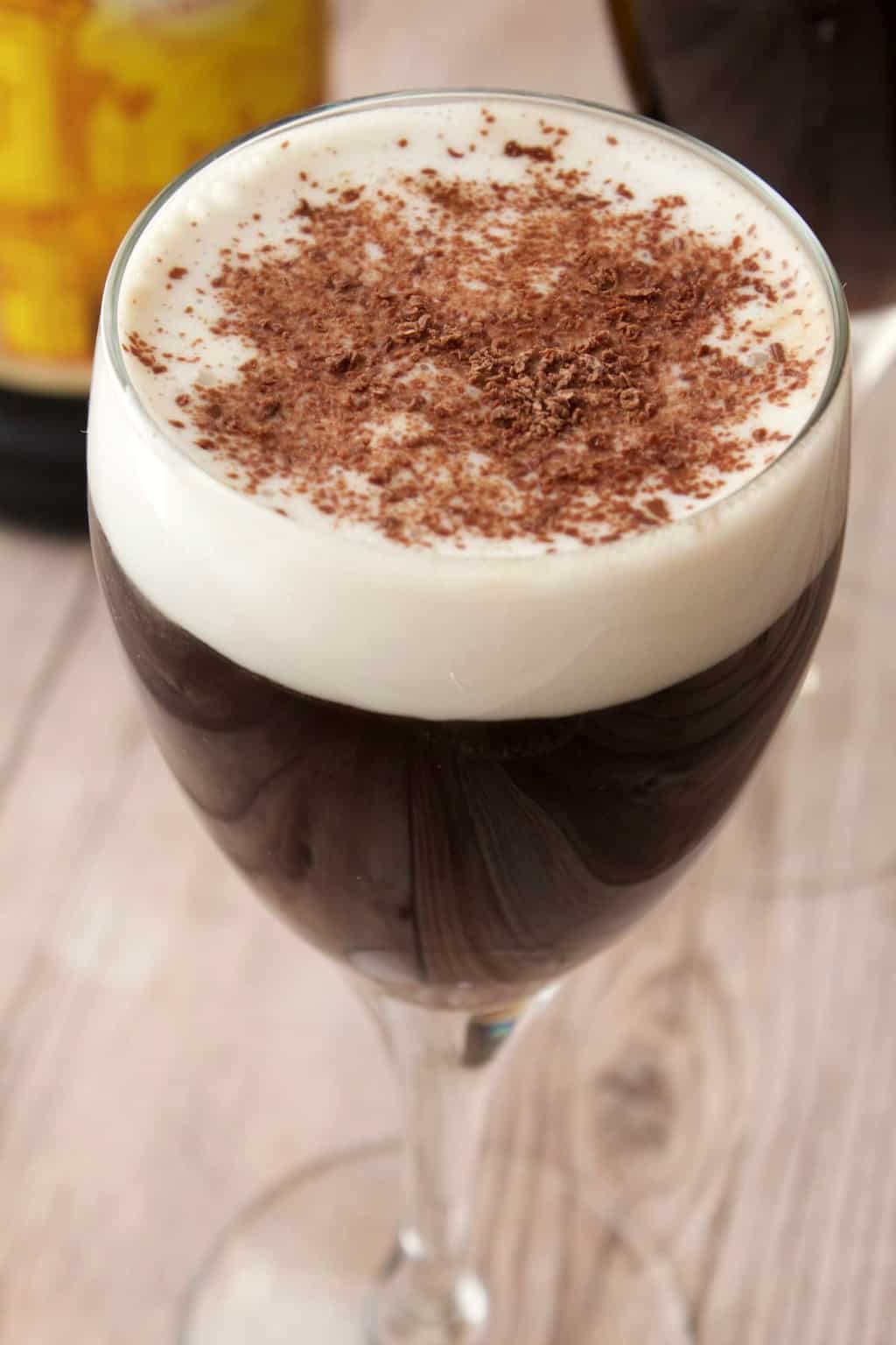Kahlua coffee in wine glasses topped with vegan whipped cream and chocolate shavings. 
