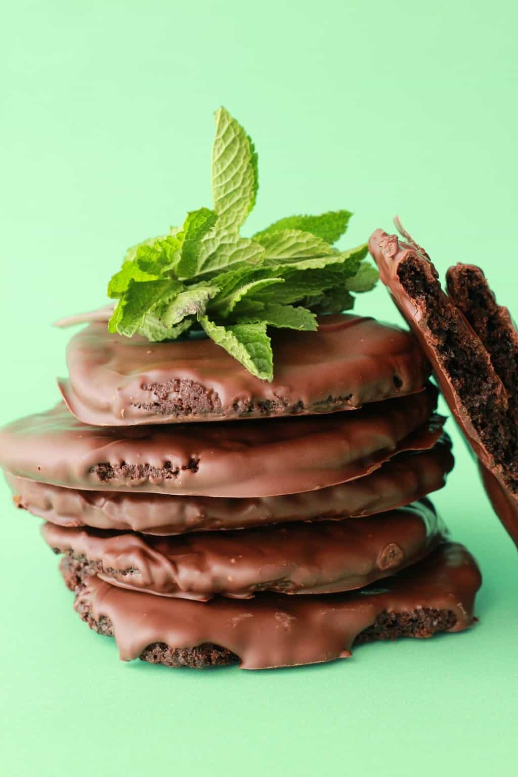 Vegan thin mint cookies stacked up against a green background. 