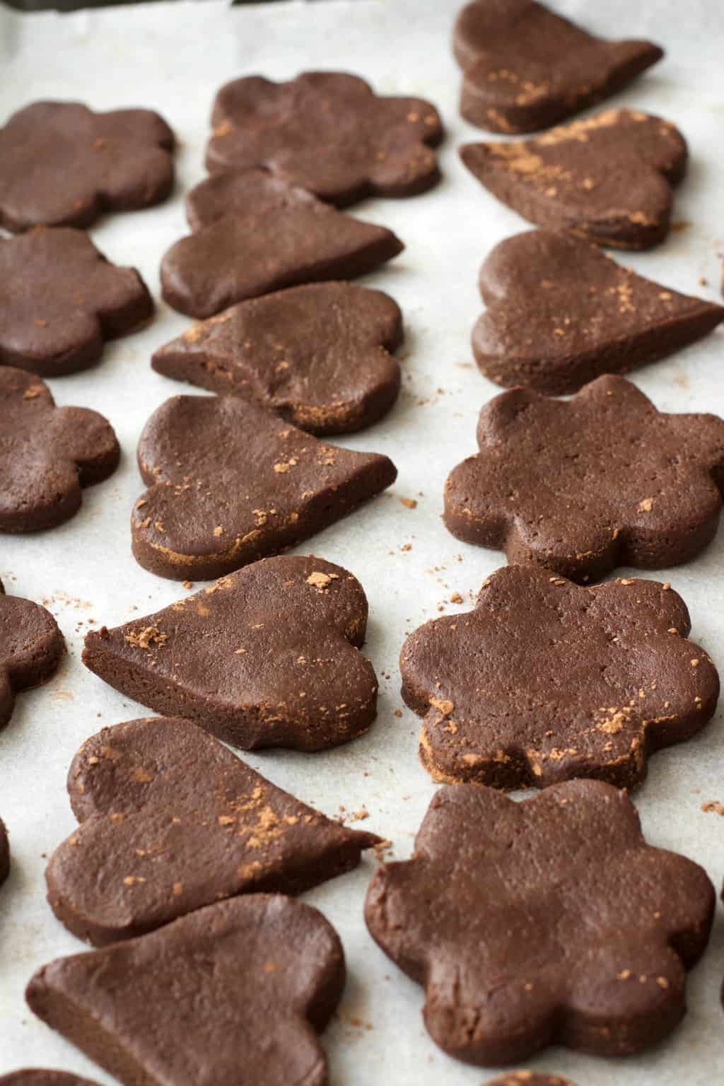 Vegan chocolate sugar cookie dough cut into shapes and ready to go into the oven to bake. 