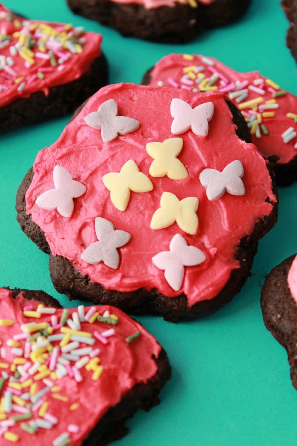 Vegan chocolate sugar cookies with pink frosting and sprinkles. 