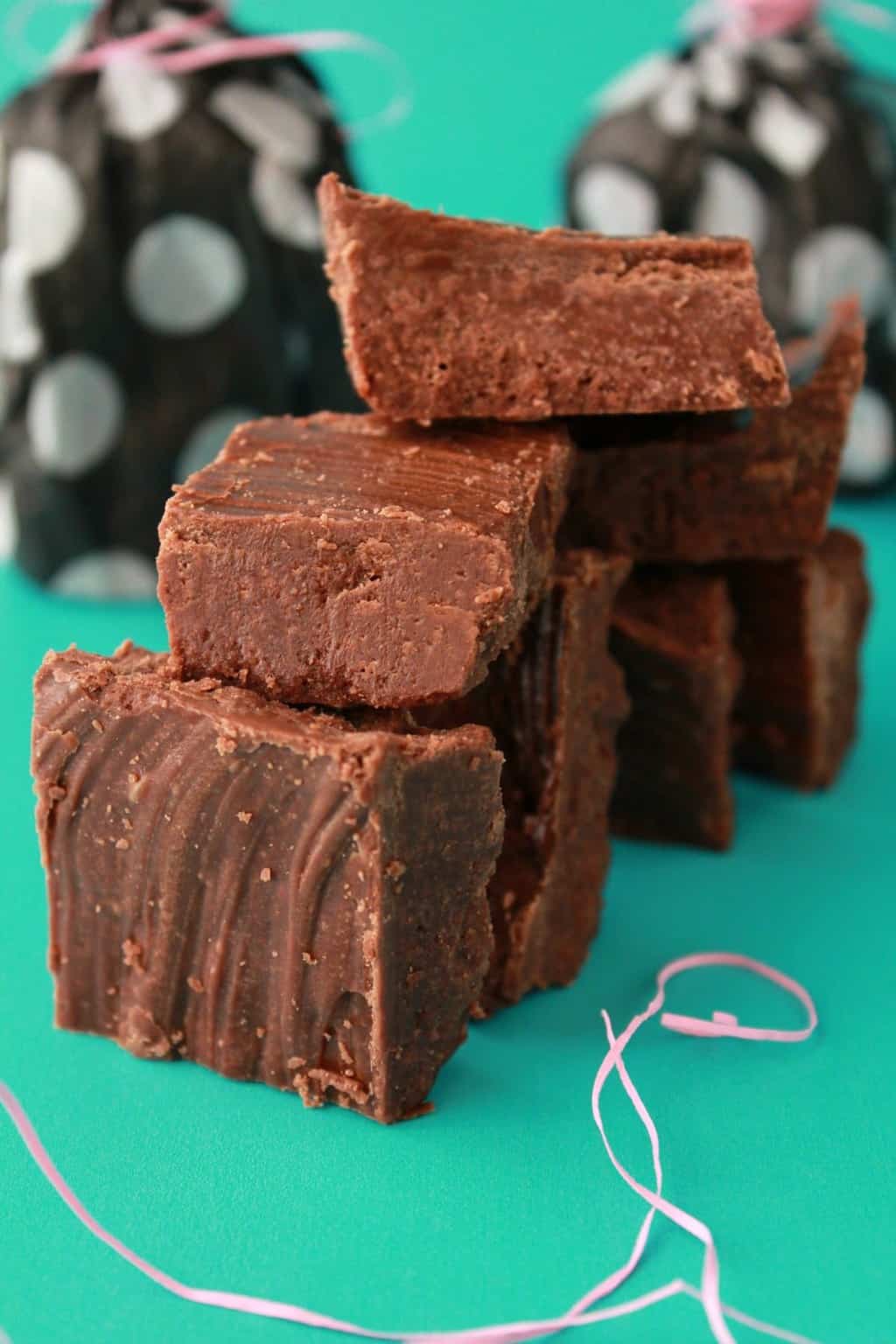 Vegan chocolate fudge squares stacked up against a green background. 