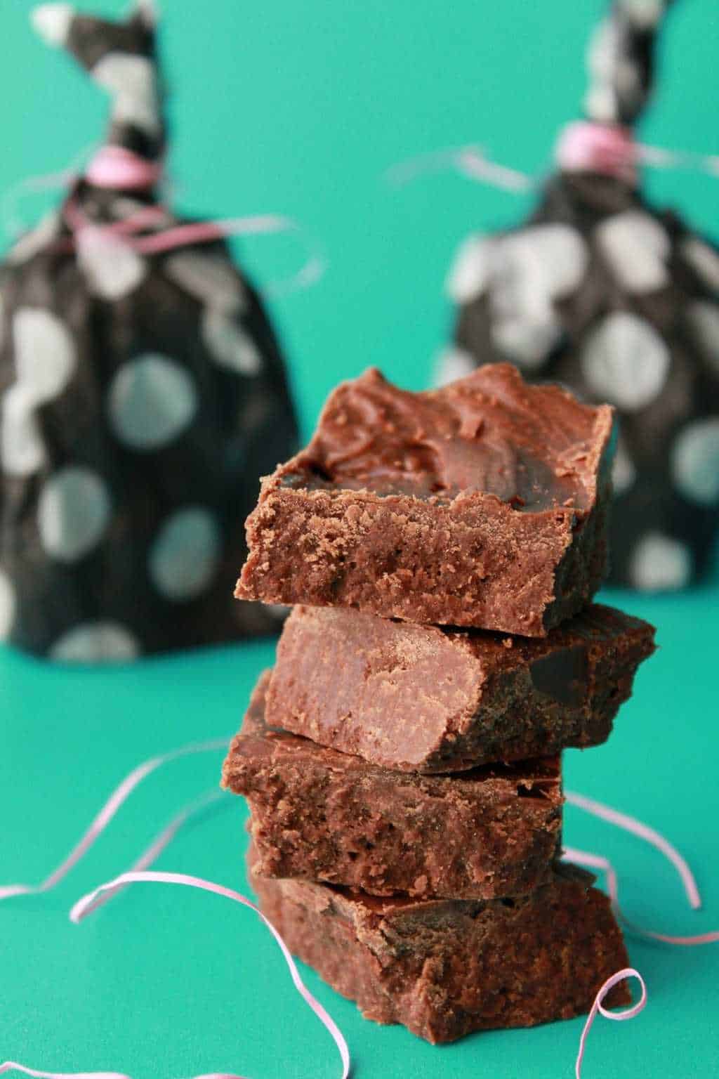 Vegan chocolate fudge squares stacked up against a green background. 