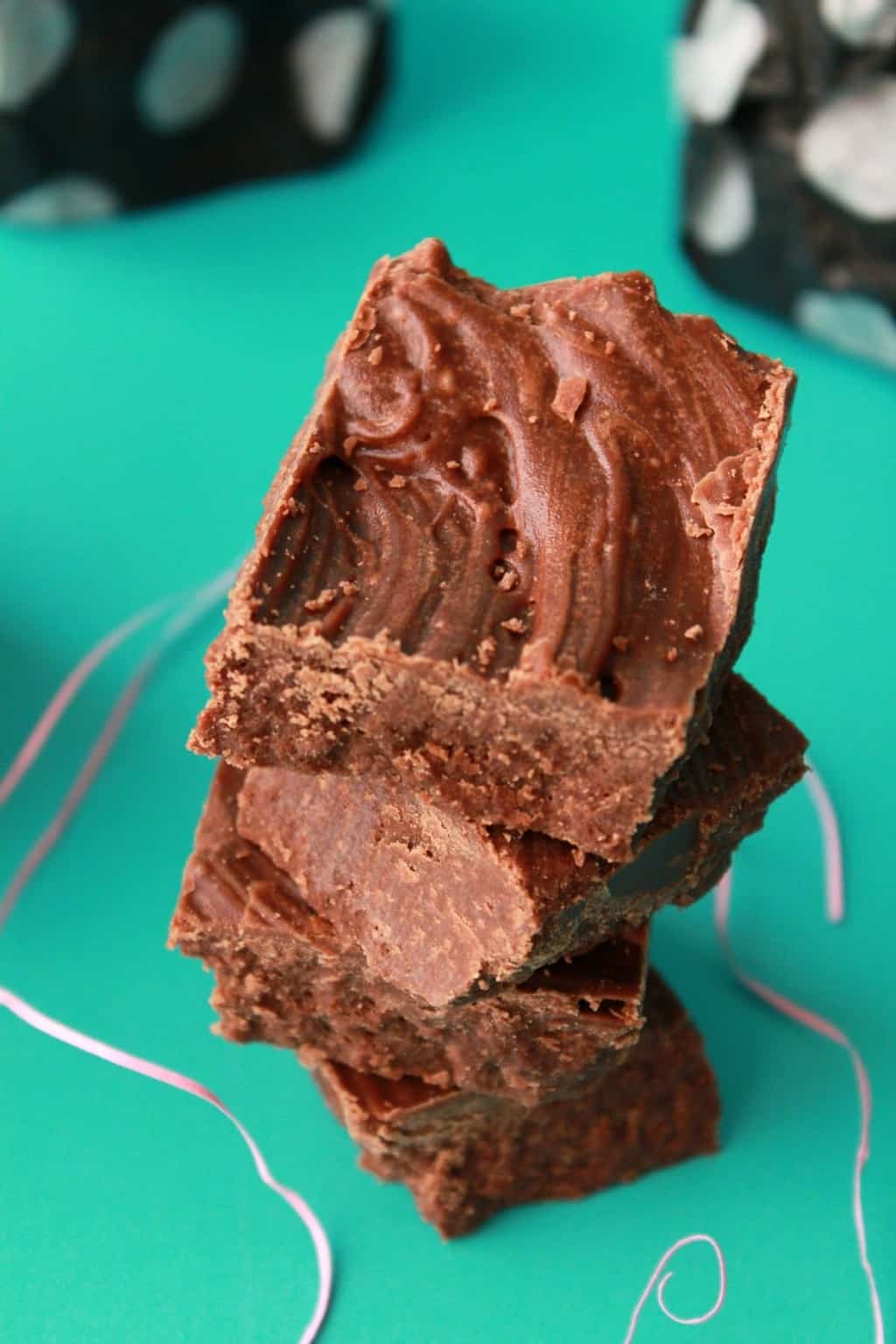 Vegan chocolate fudge stacked up against a green background. 