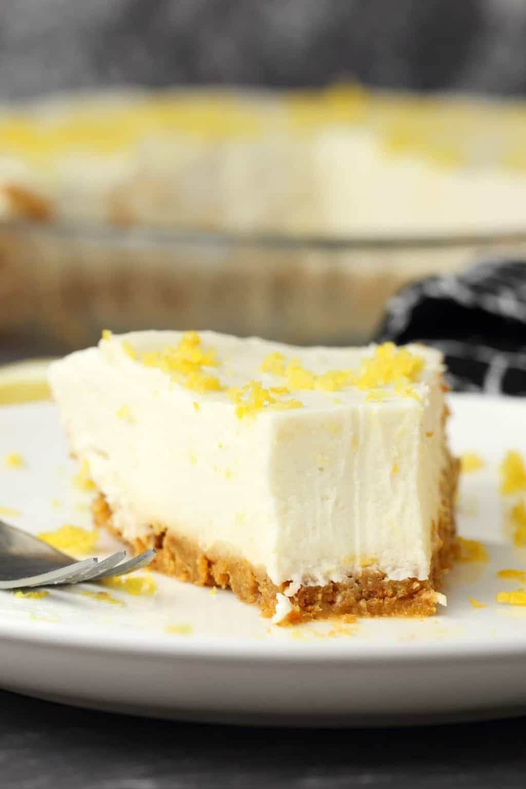 Slice of vegan lemon pie on a white plate with a cake fork. 