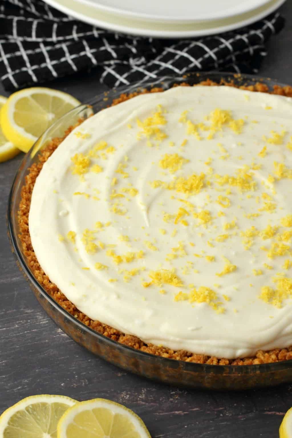 Vegan lemon pie topped with lemon zest in a glass pie dish. 
