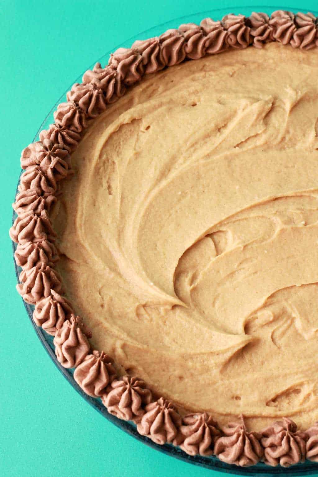 Adding some decorating touches to a vegan peanut butter pie in a glass pie dish. 