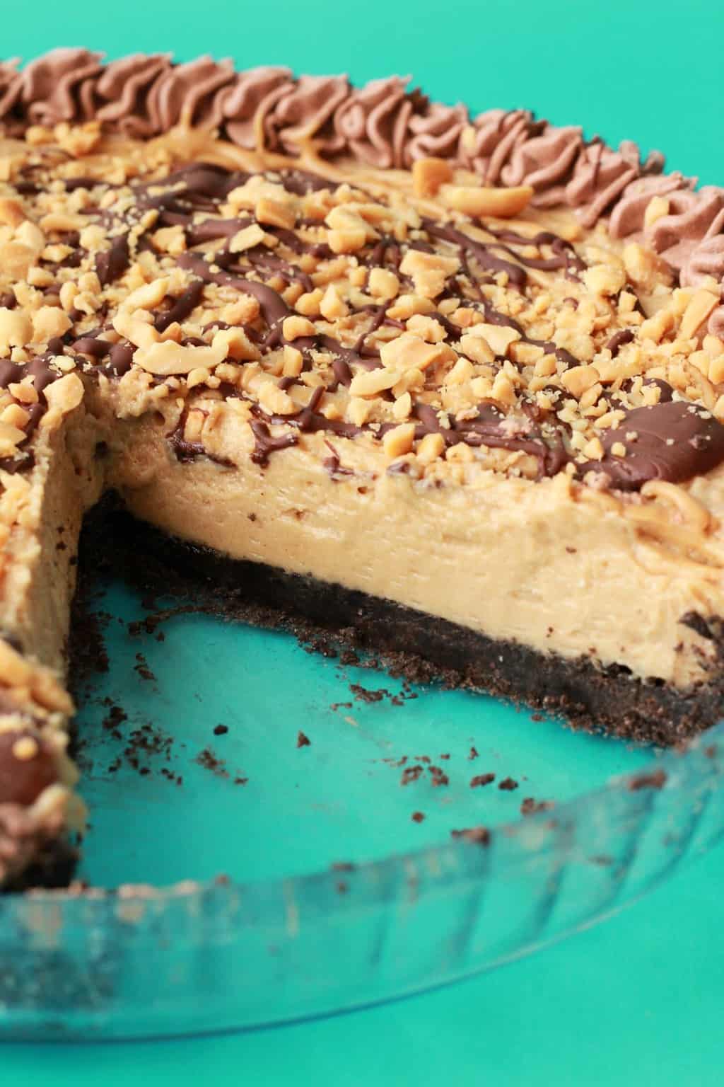 Vegan peanut butter pie in a glass pie dish with one slice removed. 