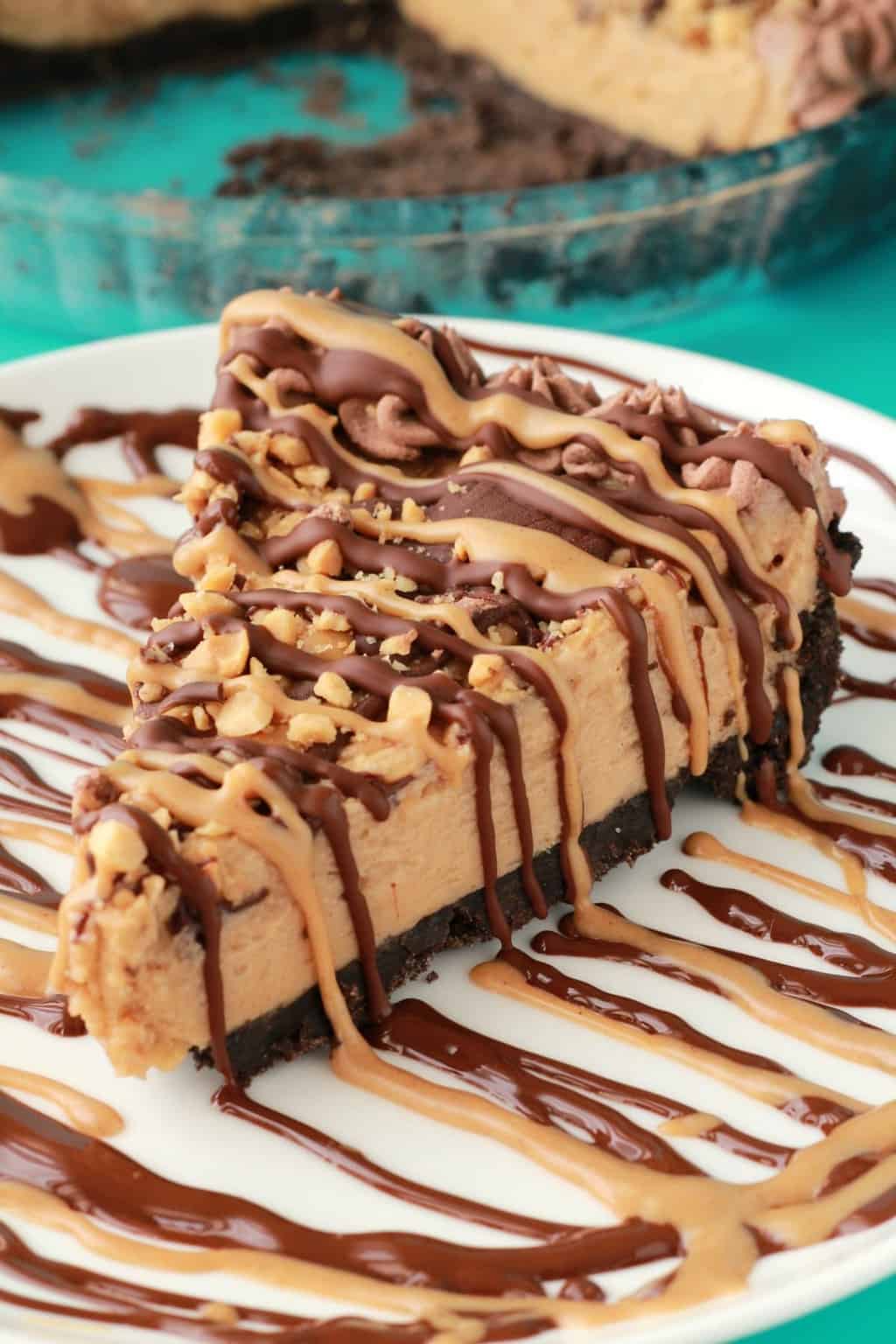 A slice of vegan peanut butter drizzled with melted peanut butter and chocolate on a white plate. 