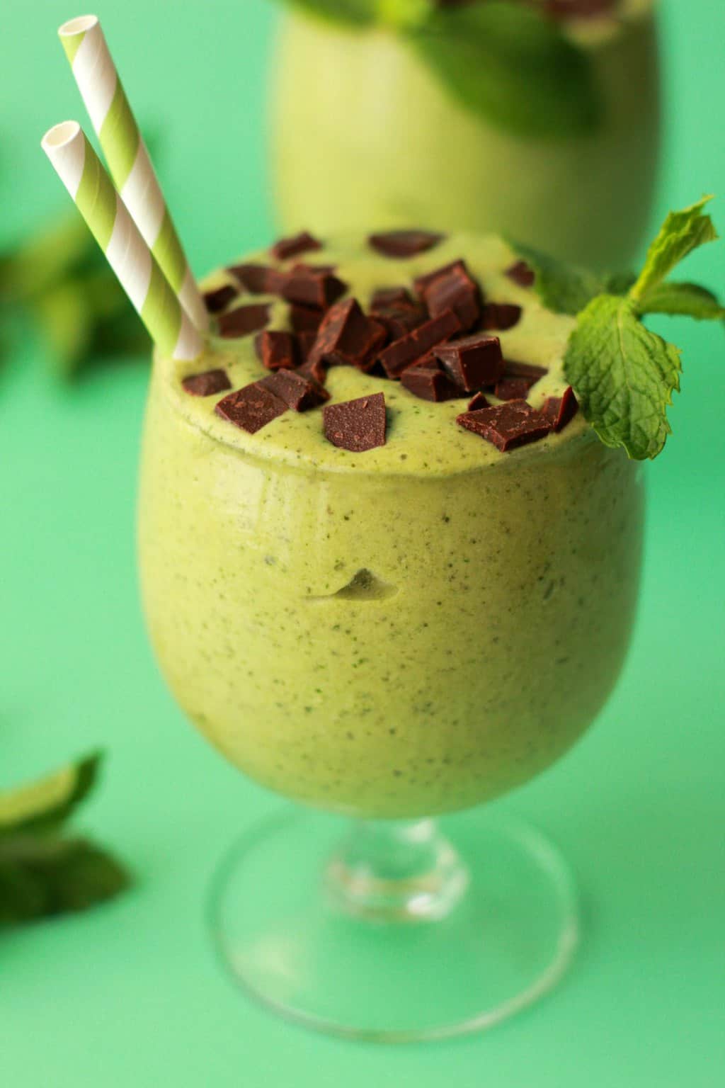 Mint smoothie in a glass with a green and white striped straw. 