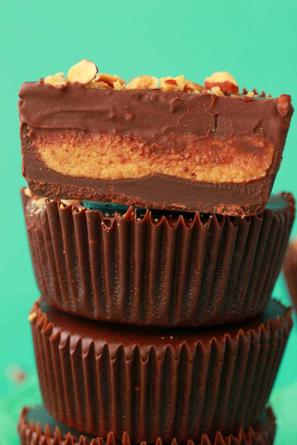 Almond butter cups in a stack, with the top one cut in half. 