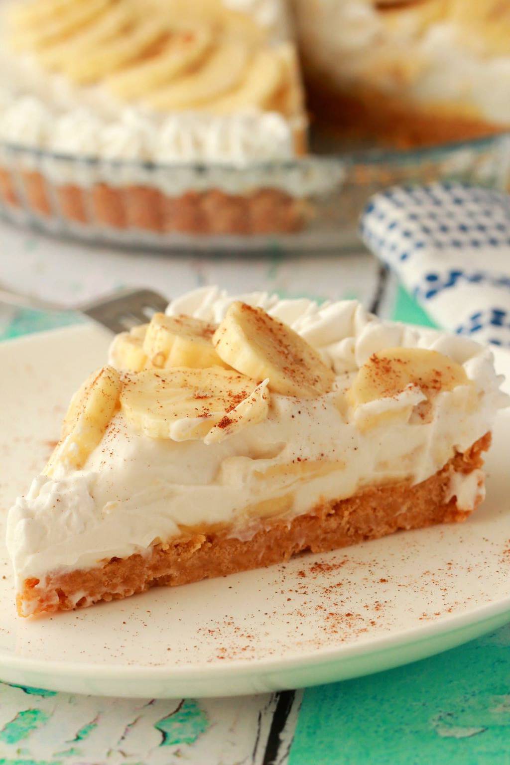 A slice of vegan banana cream pie on a white plate with a fork. 