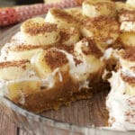 Vegan banoffee pie in a glass pie dish with slices removed.