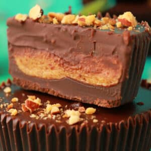 Almond butter cups in a stack of two with the top cup sliced in half.