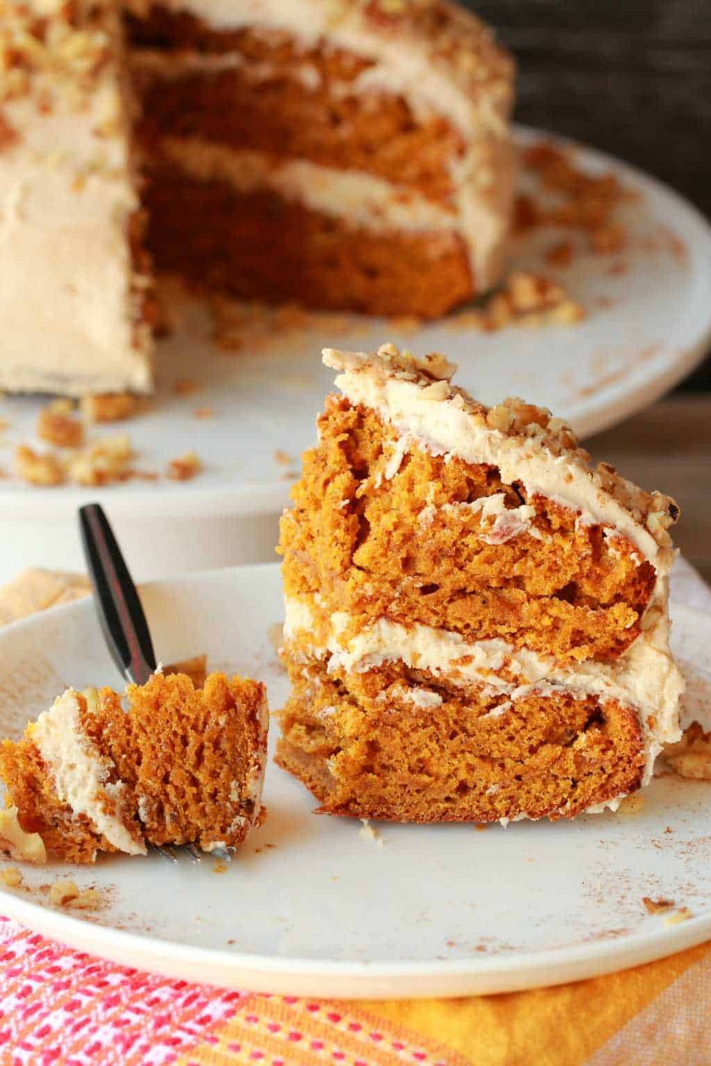 A slice of vegan pumpkin cake on a white plate with a cake fork. 