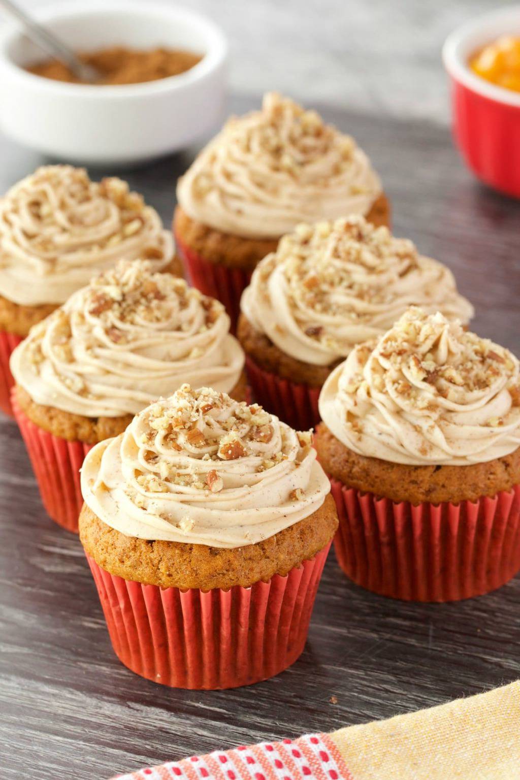 Vegan pumpkin cupcakes topped with pumpkin spice frosting and crushed pecans. 