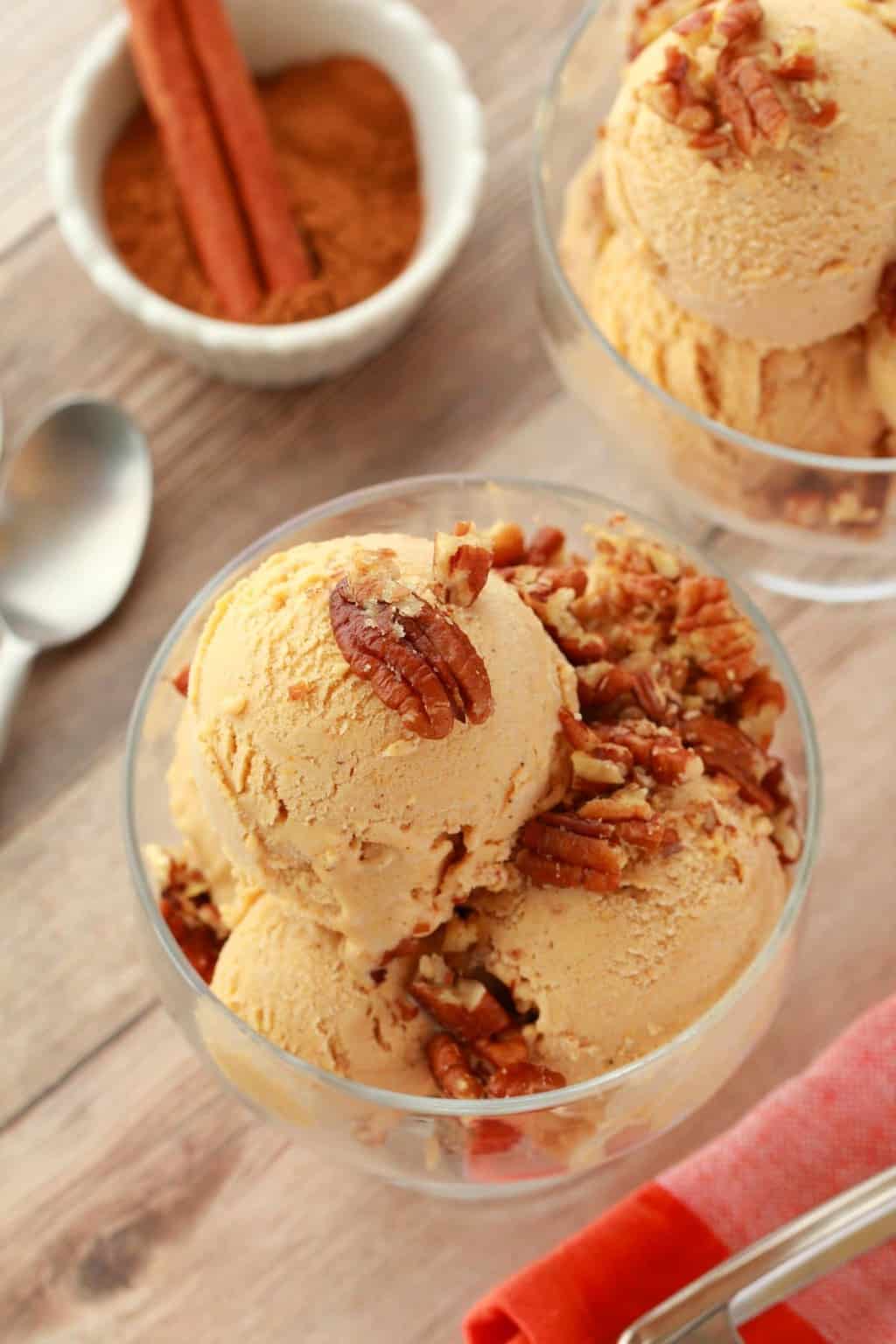 Vegan pumpkin ice cream topped with pecan nuts in a glass bowl. 