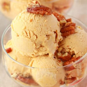 Pumpkin ice cream with pecan nuts in a glass bowl.