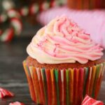 Vegan peppermint cupcake topped with frosting and crushed candy canes.