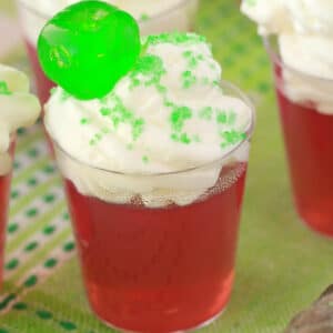 Vegan jello shots topped with vegan whipped cream, sanding sugar and a cherry.
