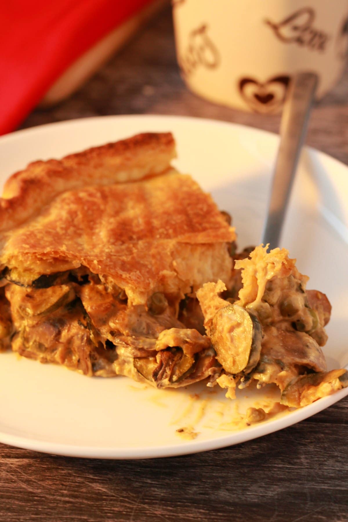 Slice of savory pie on a white plate with a fork. 