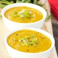 Carrot and avocado gazpacho in white bowls.