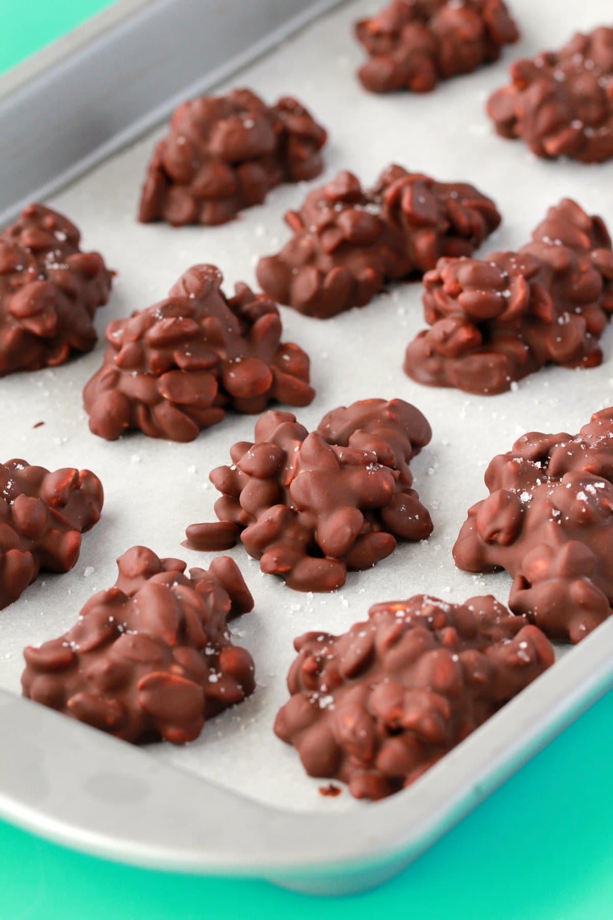 Vegan peanut clusters topped with sea salt on a parchment lined baking tray. 