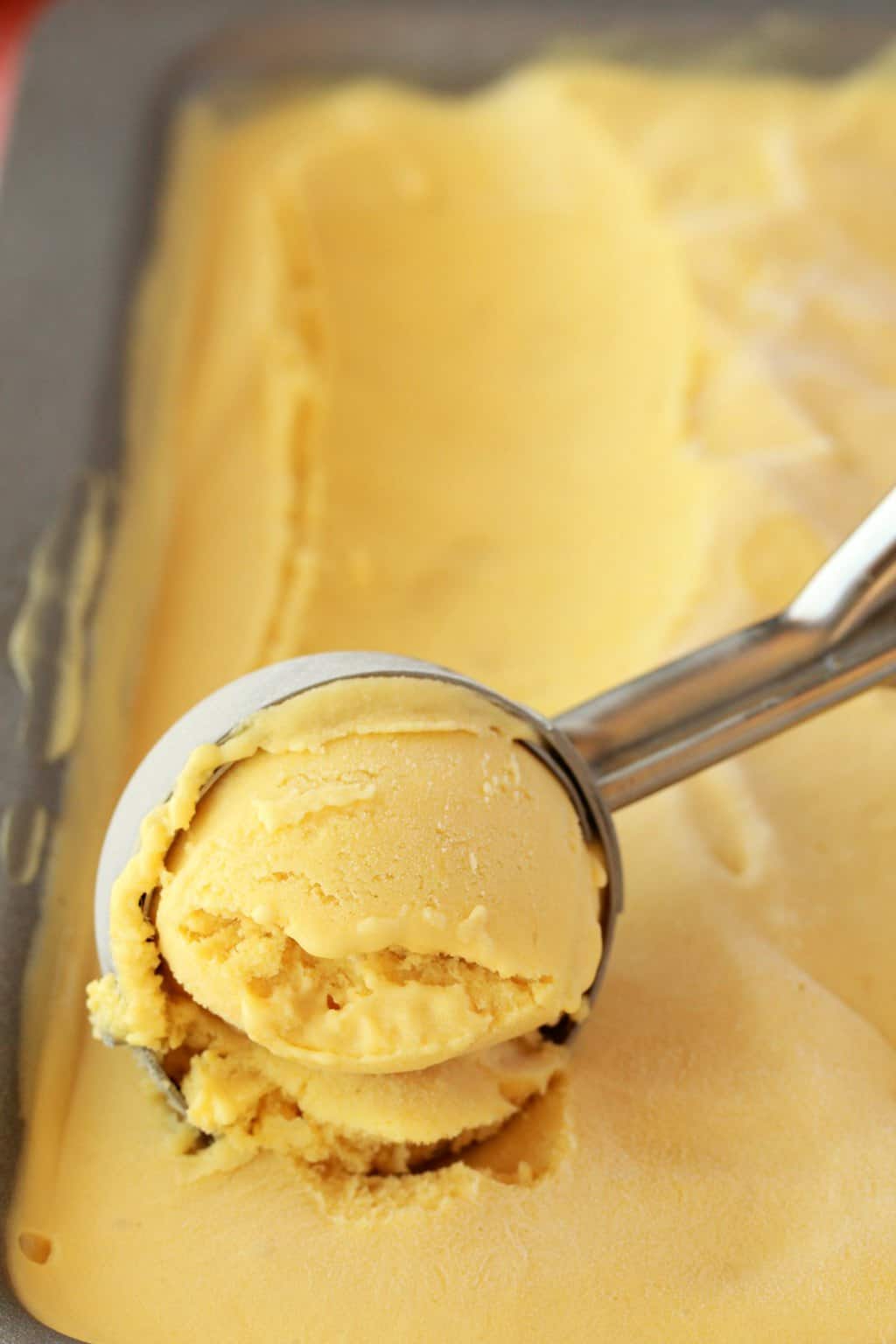 Scooping mango ice cream with an ice cream scoop. 