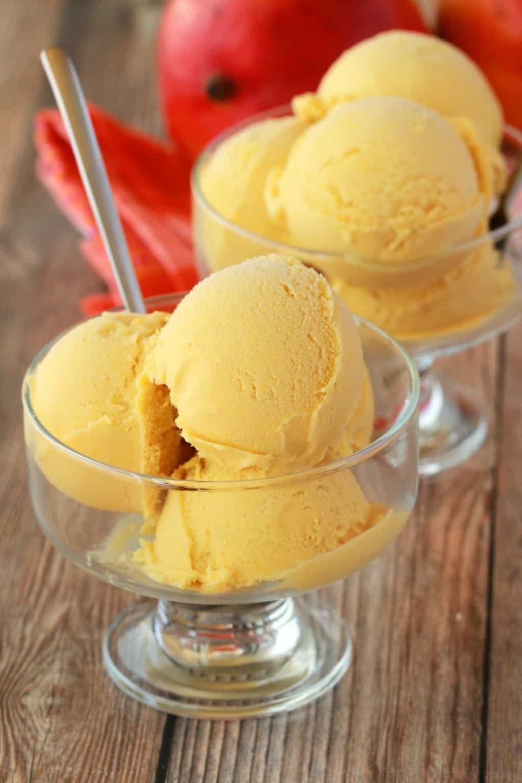 Scoops of mango ice cream in glass bowls. 