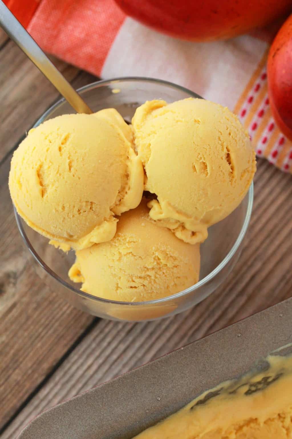 Scoops of mango ice cream in a glass bowl. 
