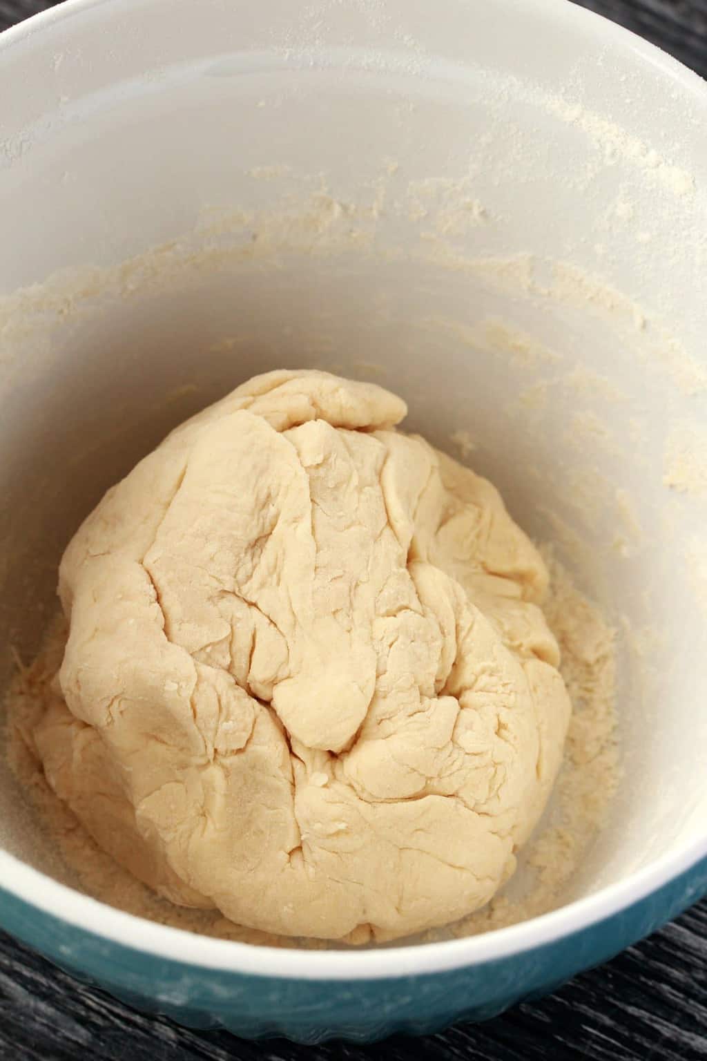 A ball of homemade pizza dough in a mixing bowl