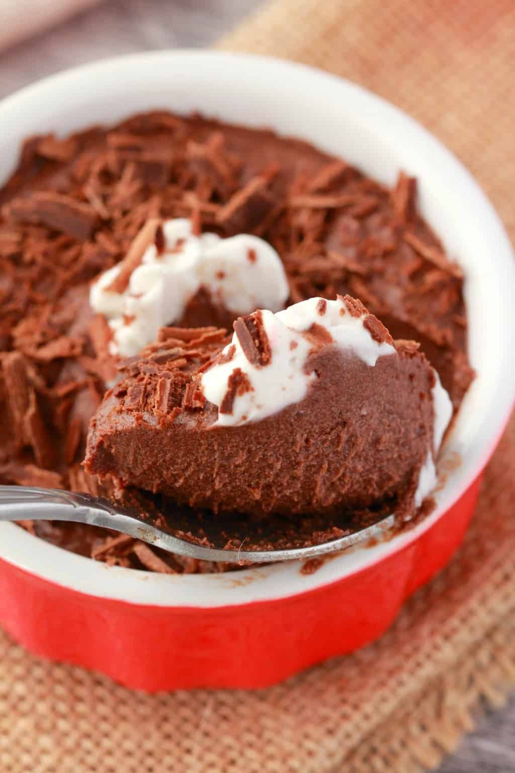Vegan chocolate mousse in a red and white ramekin with a teaspoon.