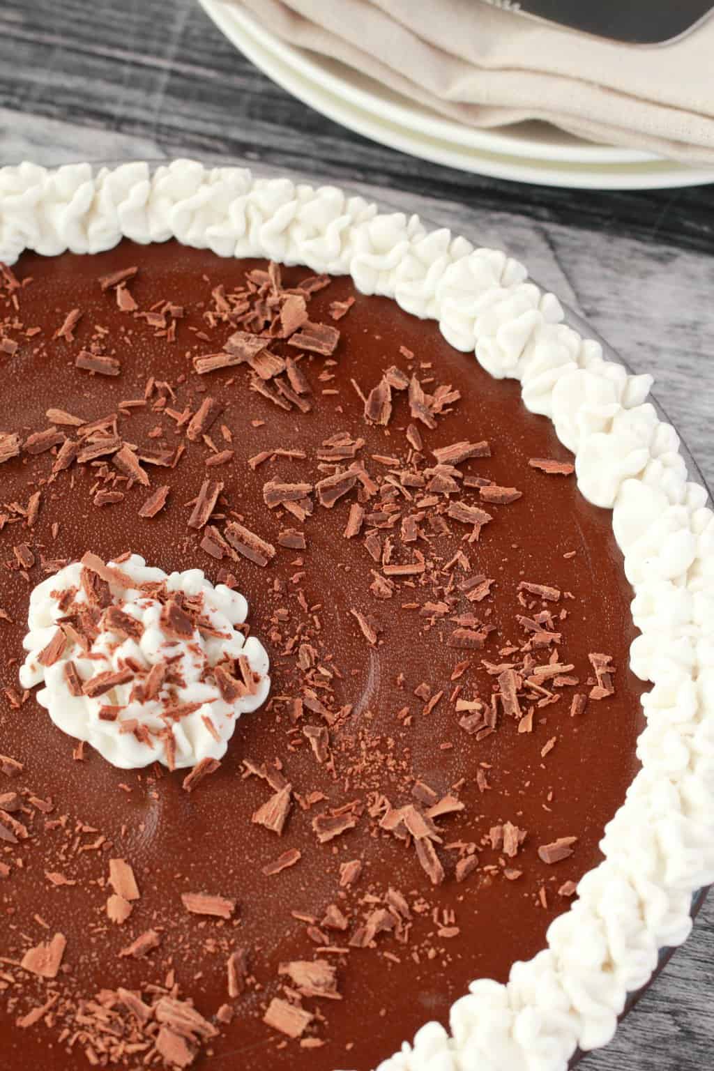 Vegan chocolate pie with whipped coconut cream and chocolate flakes in a glass dish. 