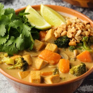 Vegan massaman curry in a bowl with fresh lime and cilantro.