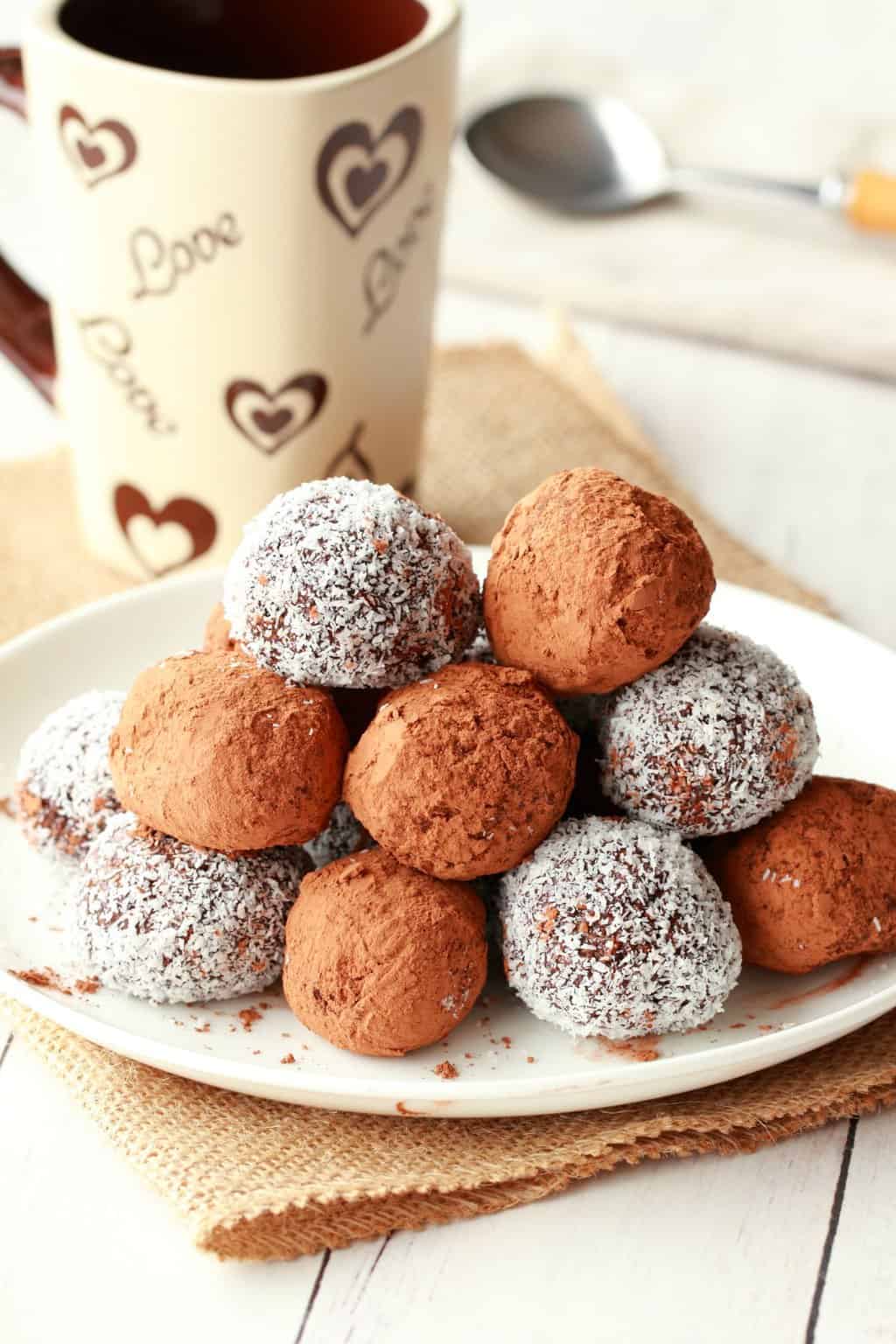 Vegan Truffles on a white plate with a coffee cup in the background