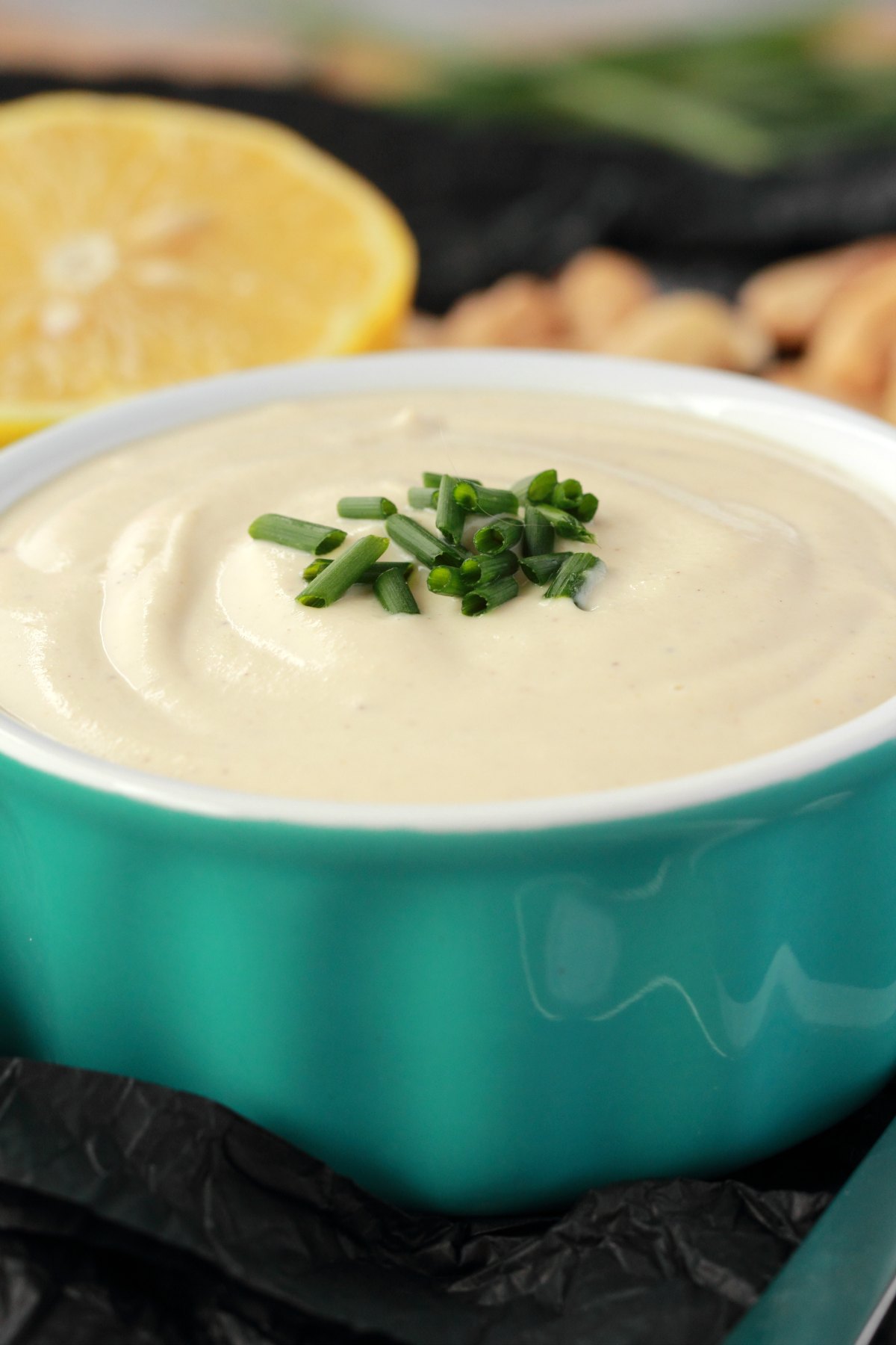 Cashew cream in a turquoise and white ramekin with chopped chives on top. 