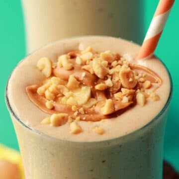 Peanut butter banana smoothie in glasses with straws.