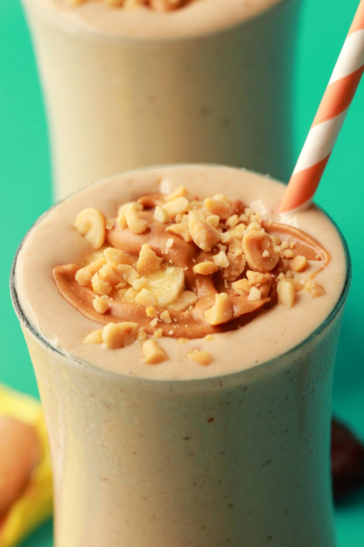 Peanut Butter Banana Smoothie in a glass with an orange and white straw. 