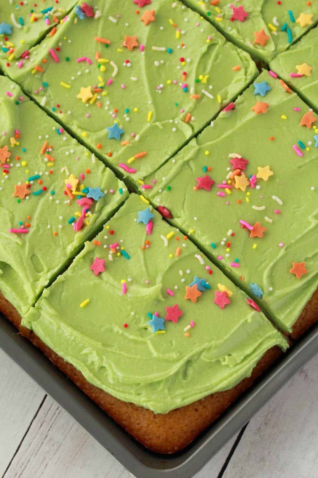 Vanilla sheet cake with green frosting and sprinkles.
