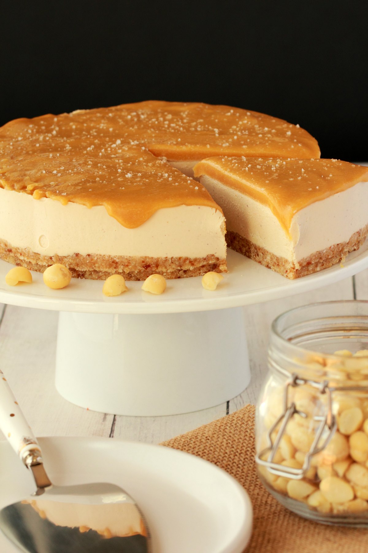 Vegan cheesecake on a cake stand with one slice cut and ready to be served. 