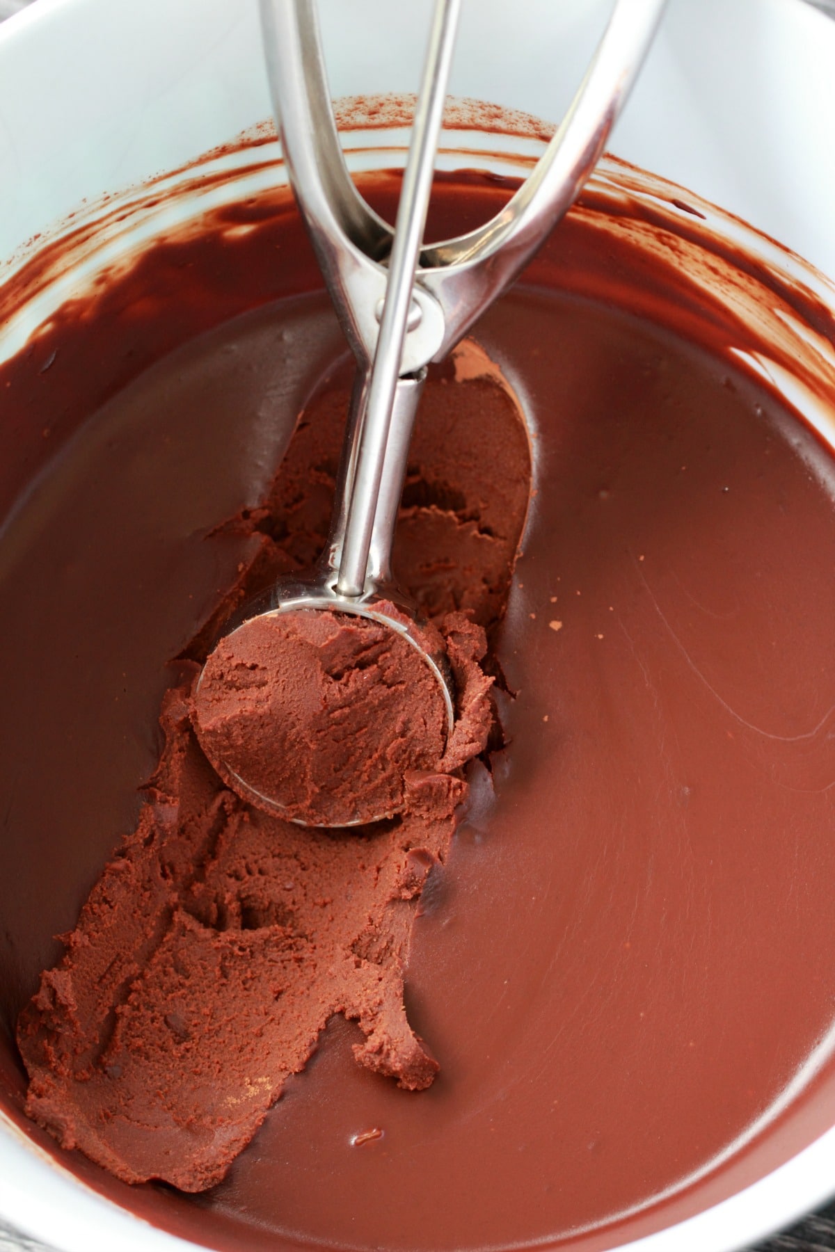 Scooping out hard set chocolate ganache with an ice cream scoop. 