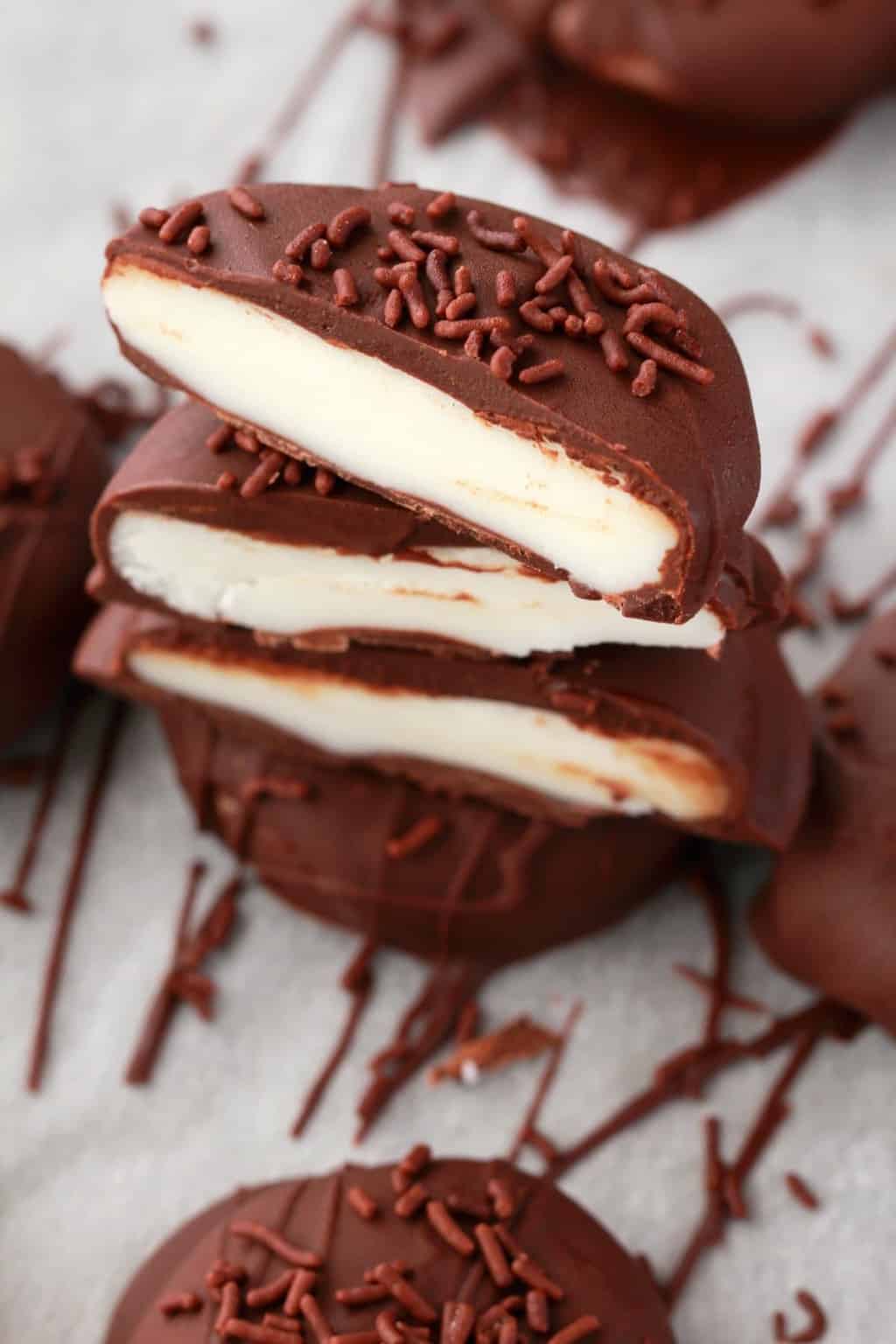Vegan peppermint patties stacked up and cut in half to show their centers. 