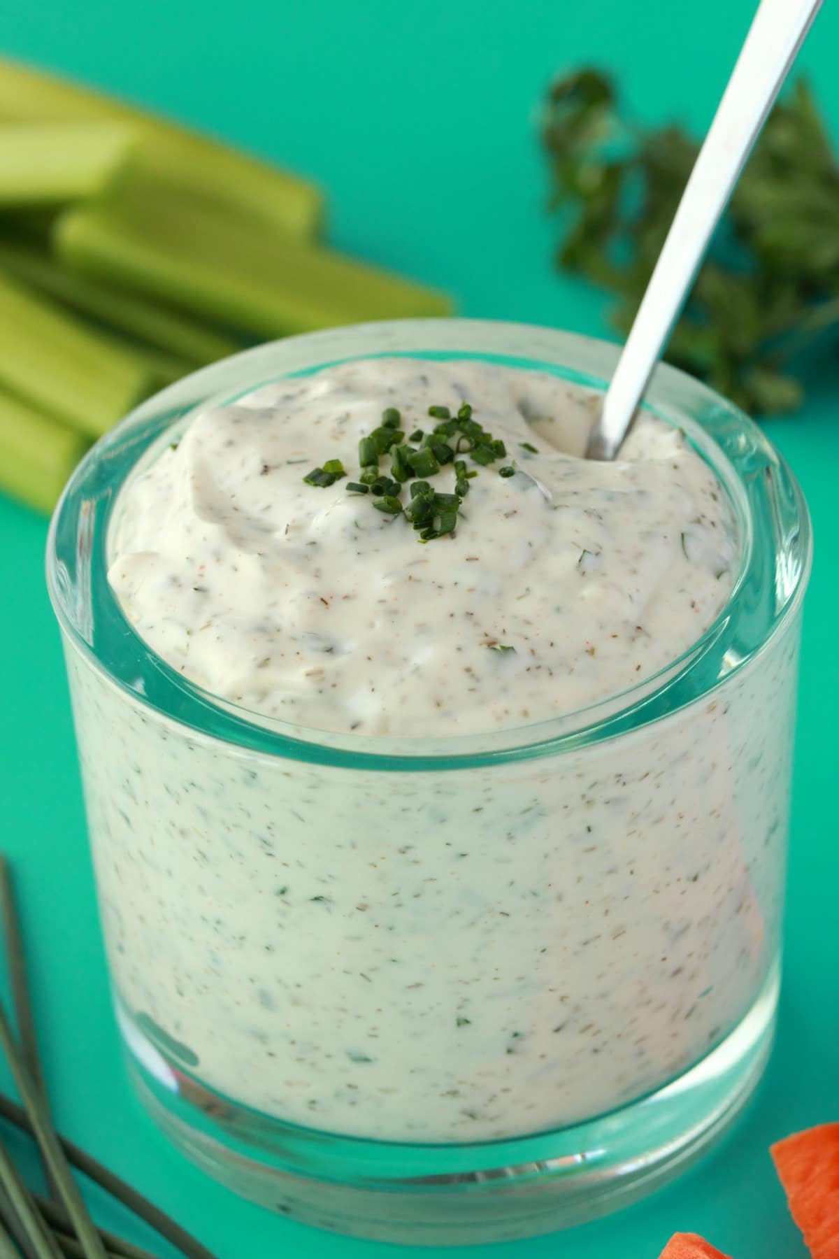 Vegan ranch dressing topped with chopped chives in a glass jar with a spoon. 