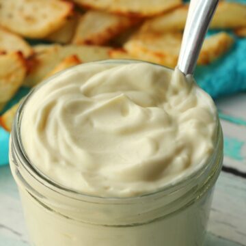 Vegan mayo in a glass jar with a spoon.