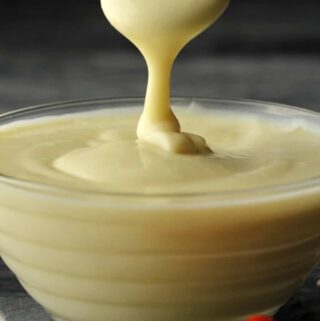 Vegan mayonnaise in a glass bowl with a spoon.