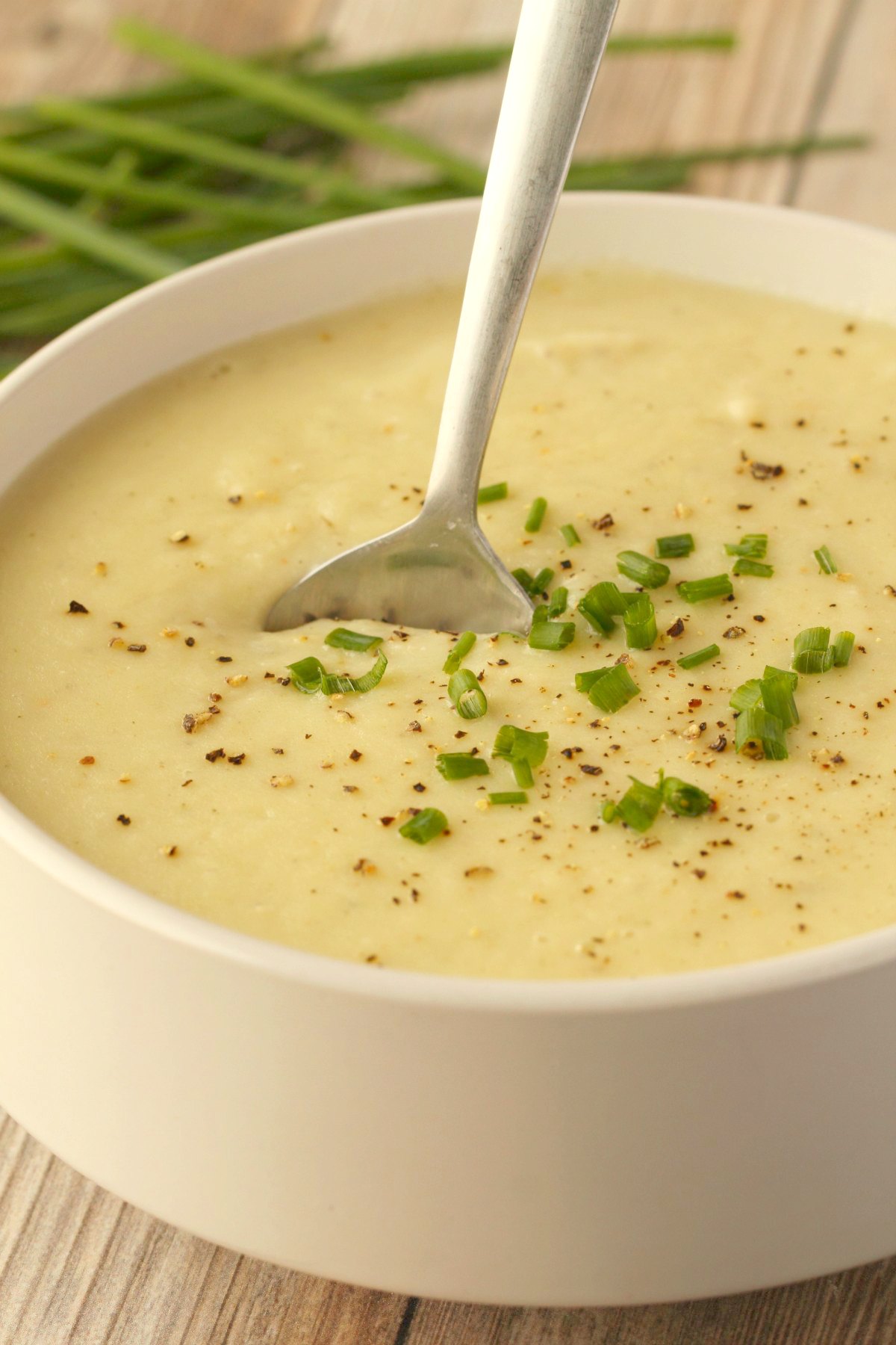 Vegan potato leek soup in a white bowl with a spoon. 