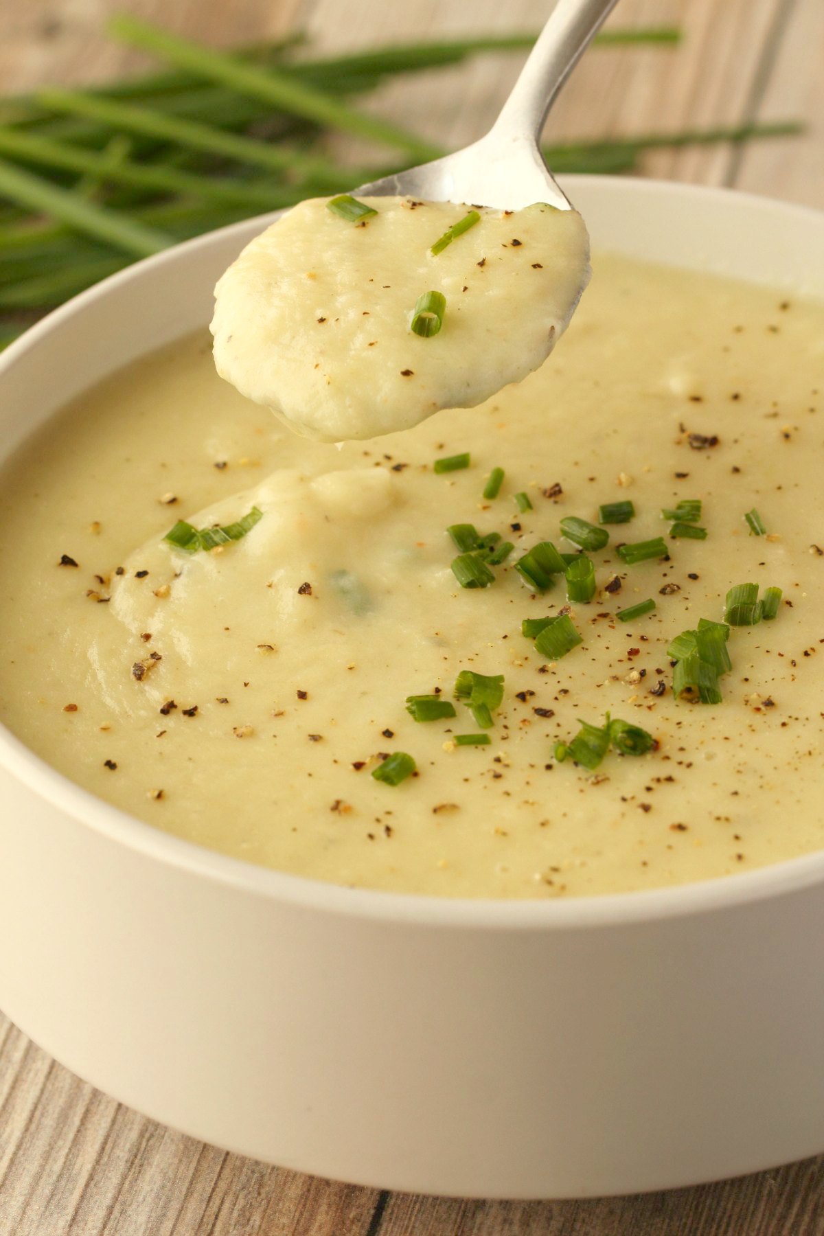 Vegan potato leek soup in a white bowl with a spoon. 