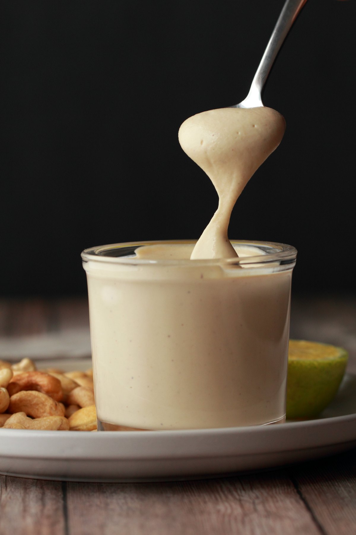 A spoon dipping into a jar full of vegan sour cream. 
