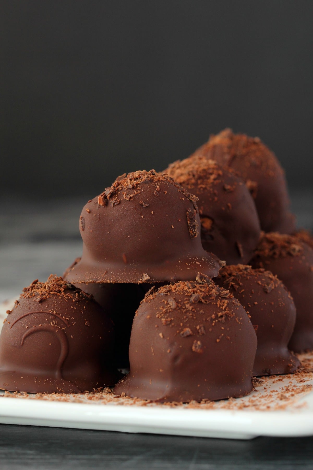 Vegan Chocolate Truffles stacked up on a white plate.