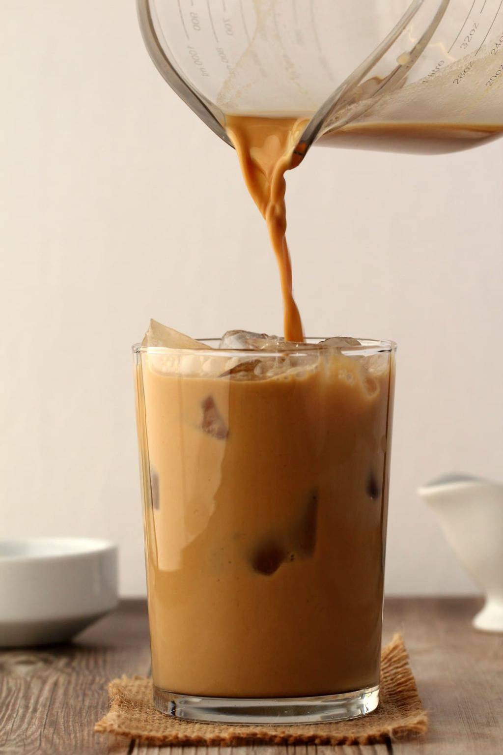 Vegan Iced Coffee pouring from a jug into a glass full of ice. 