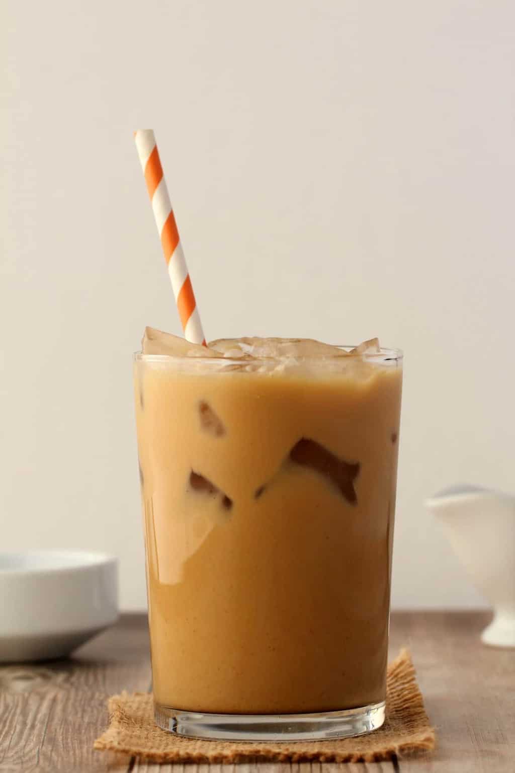 Vegan Iced Coffee in a glass with an orange and white striped straw. 